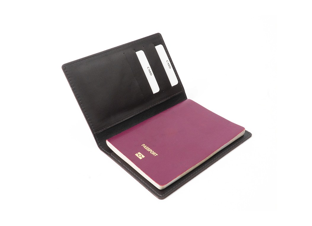An open dark brown leather passport holder revealing a maroon passport inside and card slots on the left flap.