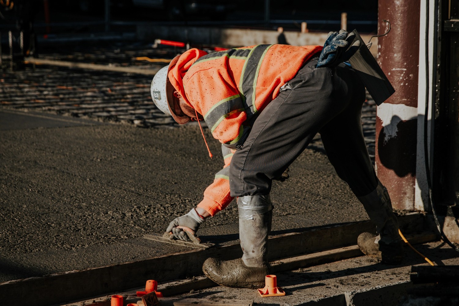 Ouvrier nivelant du béton frais sur un chantier de voirie.