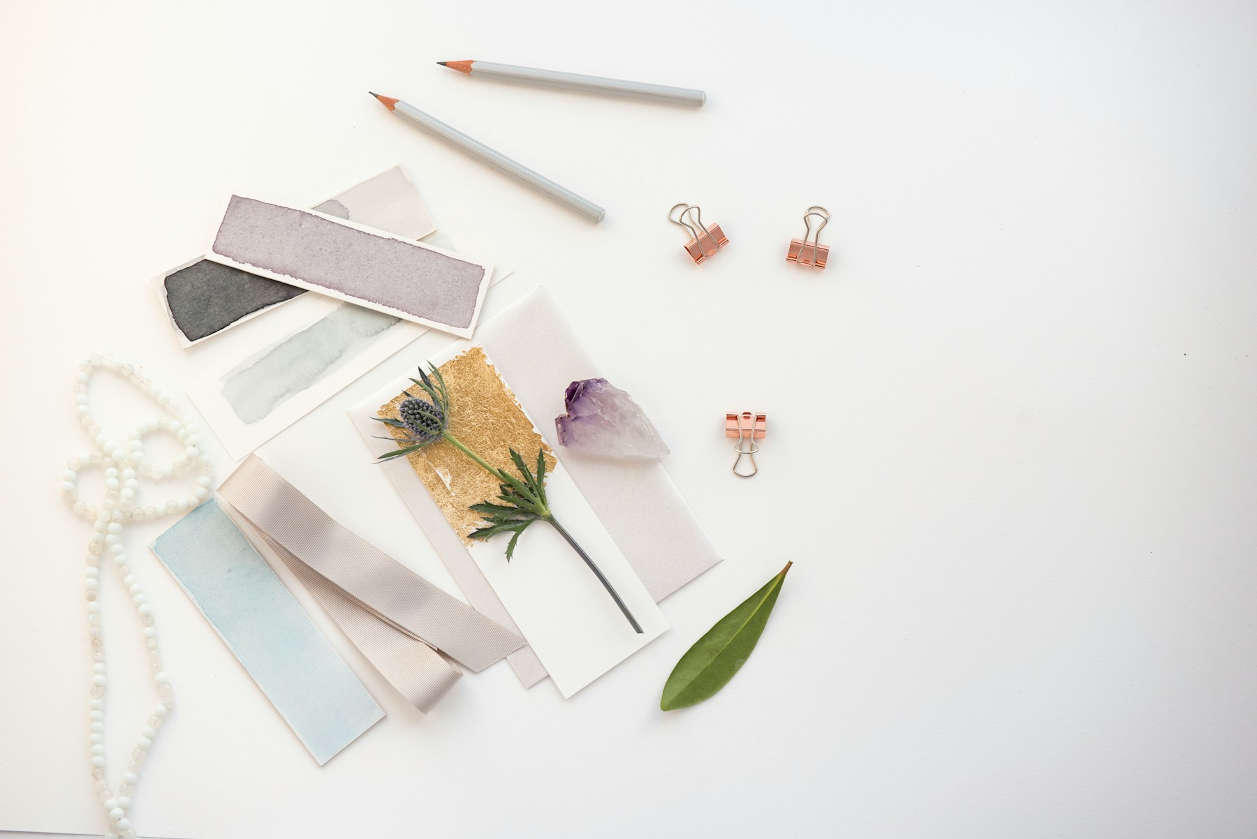 Tile and paint samples laid out with pencils and a leaf