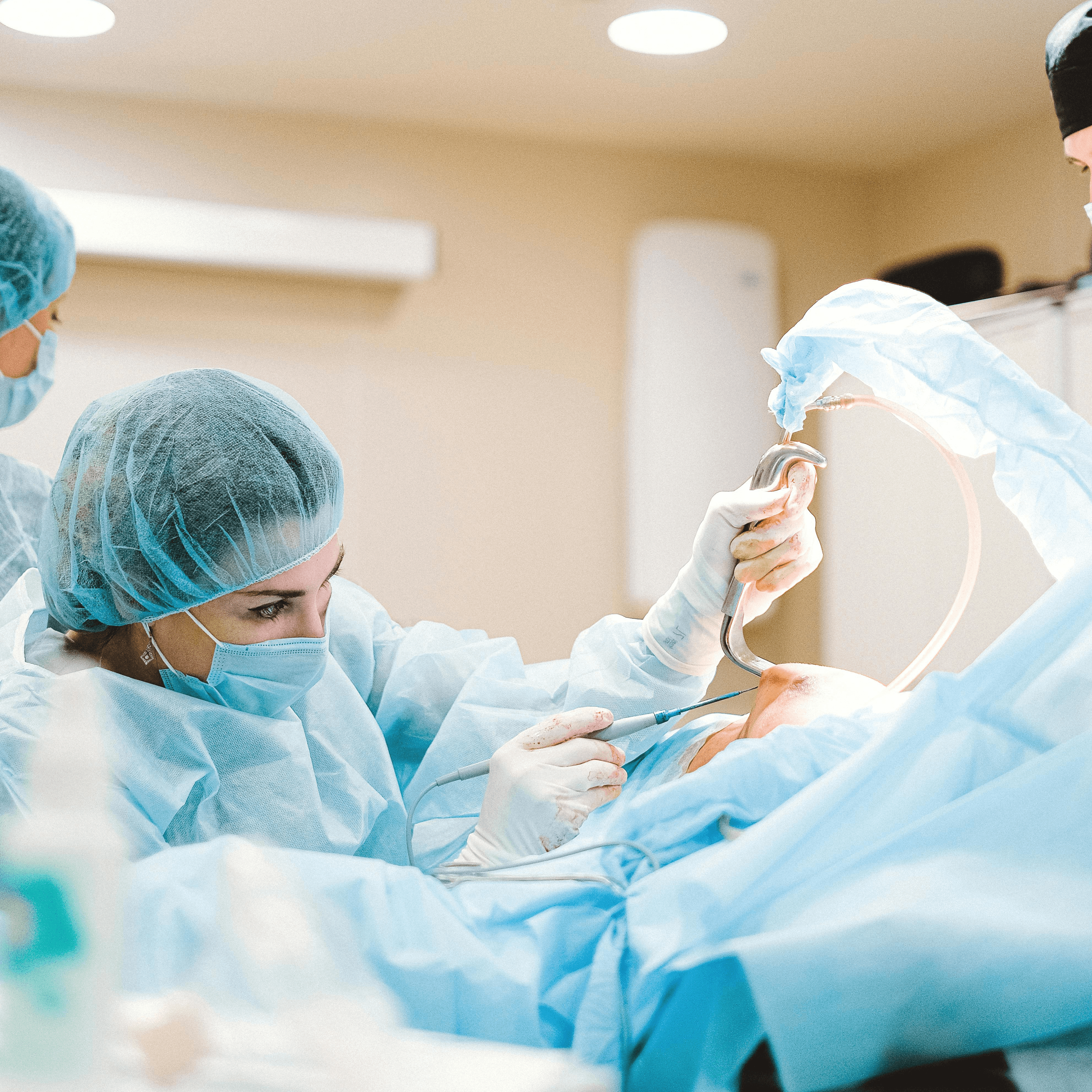 An anesthesia provider in surgical cap and mask cares for a patient in an operating room setting