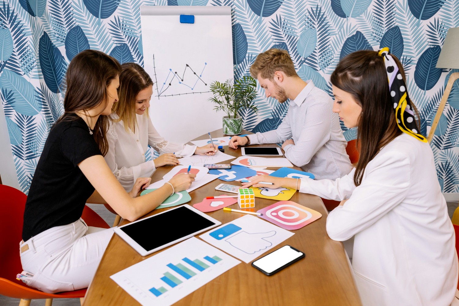 A diverse group of individuals gathered around a table, engaged with a tablet in a collaborative discussion.