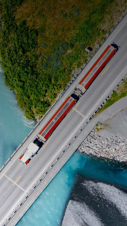 Aerial view of a semi-truck driving across a bridge over blue water representing truck insurance services