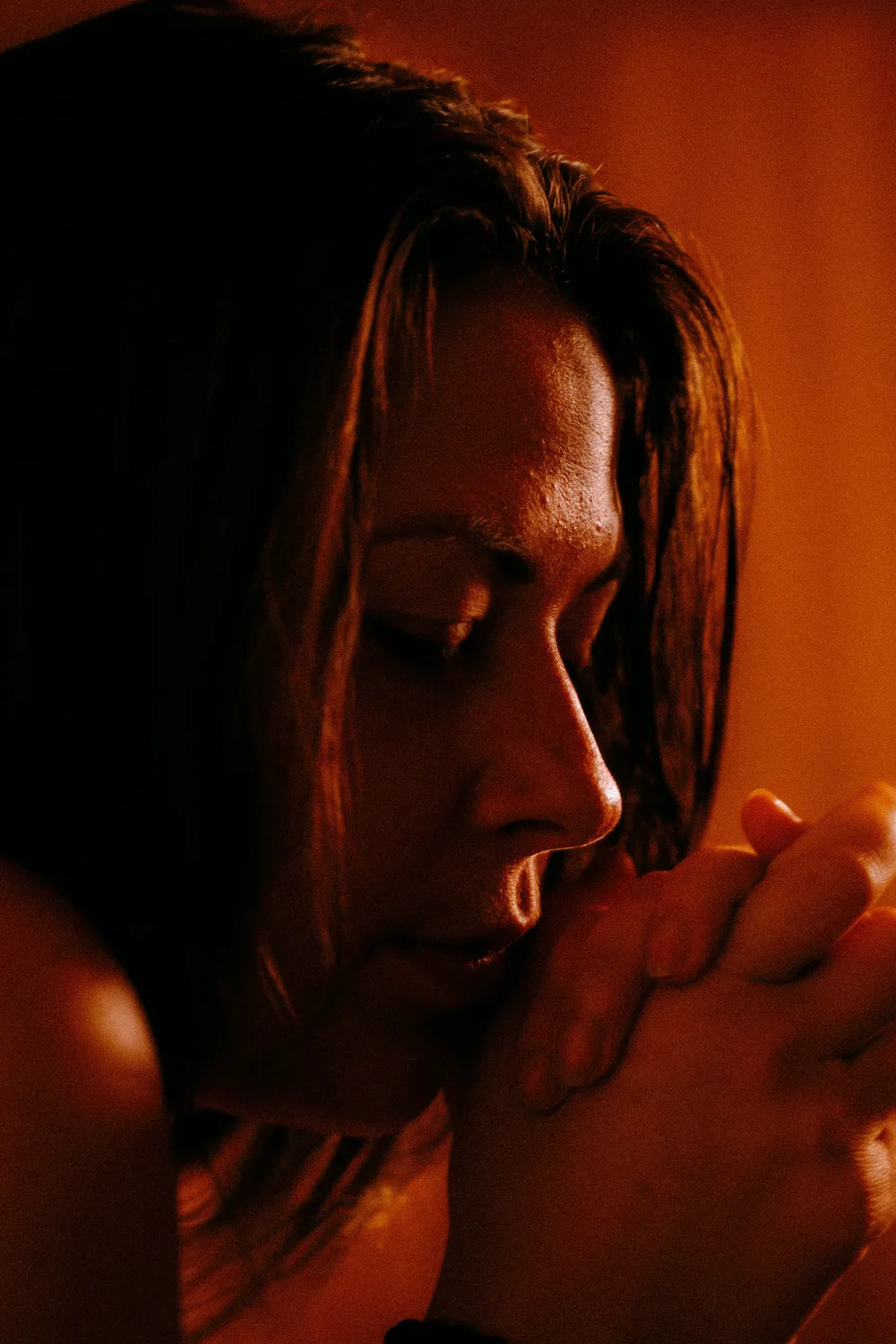Close-up of a person with eyes closed and hands clasped during a quiet meditative ritual in Vancouver.