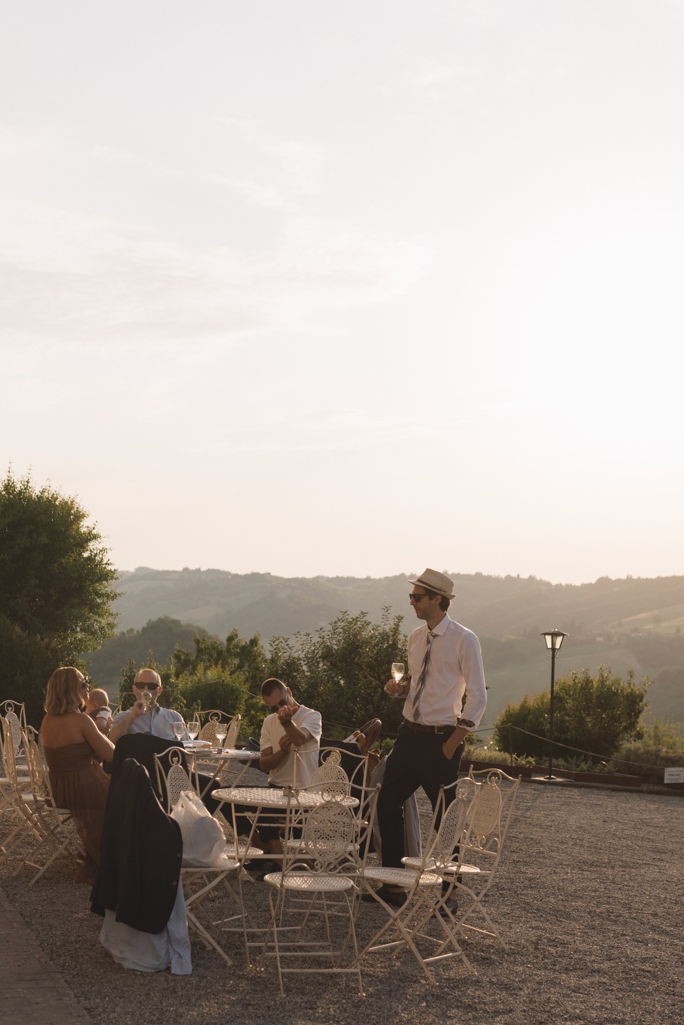 Ospiti seduti al tavolo durante il ricevimento di matrimonio al Parco di Montebello, al tramonto