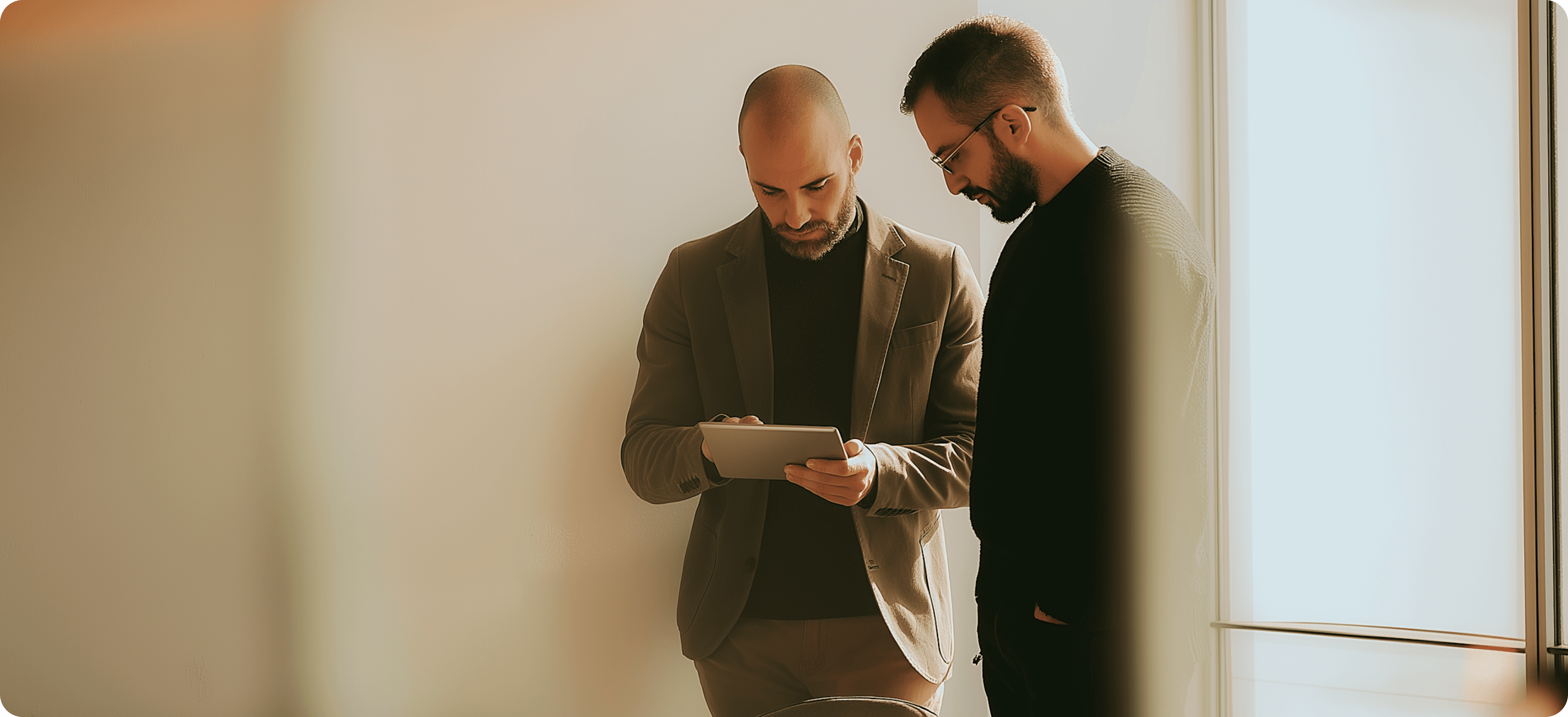 Two men looking at a tablet together in an office.