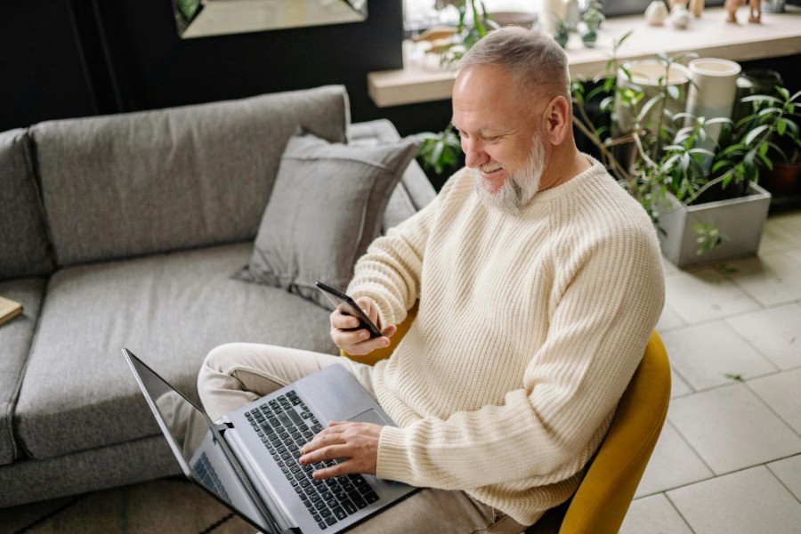 Persona revisando sus inversiones desde el celular y una laptop en casa