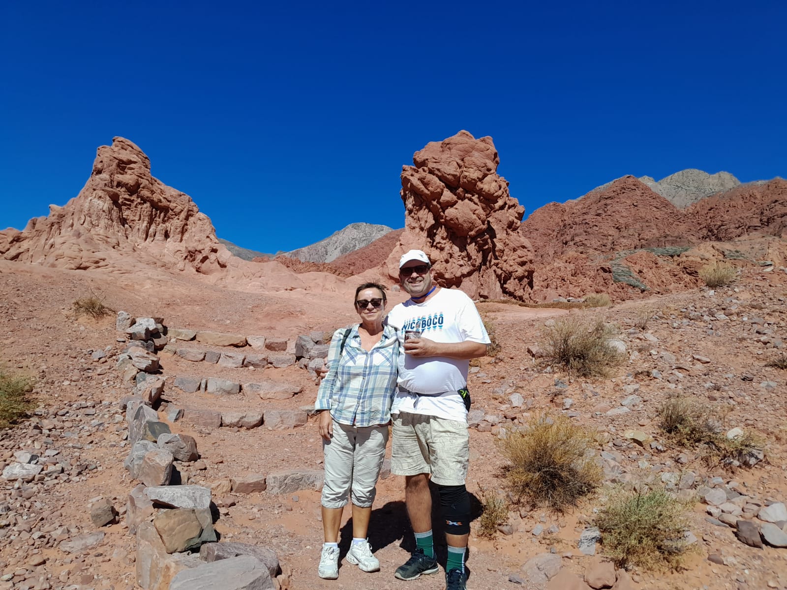 Mujer sentada sobre un tronco frente a una cascada doble en un bosque frondoso de Argentina.