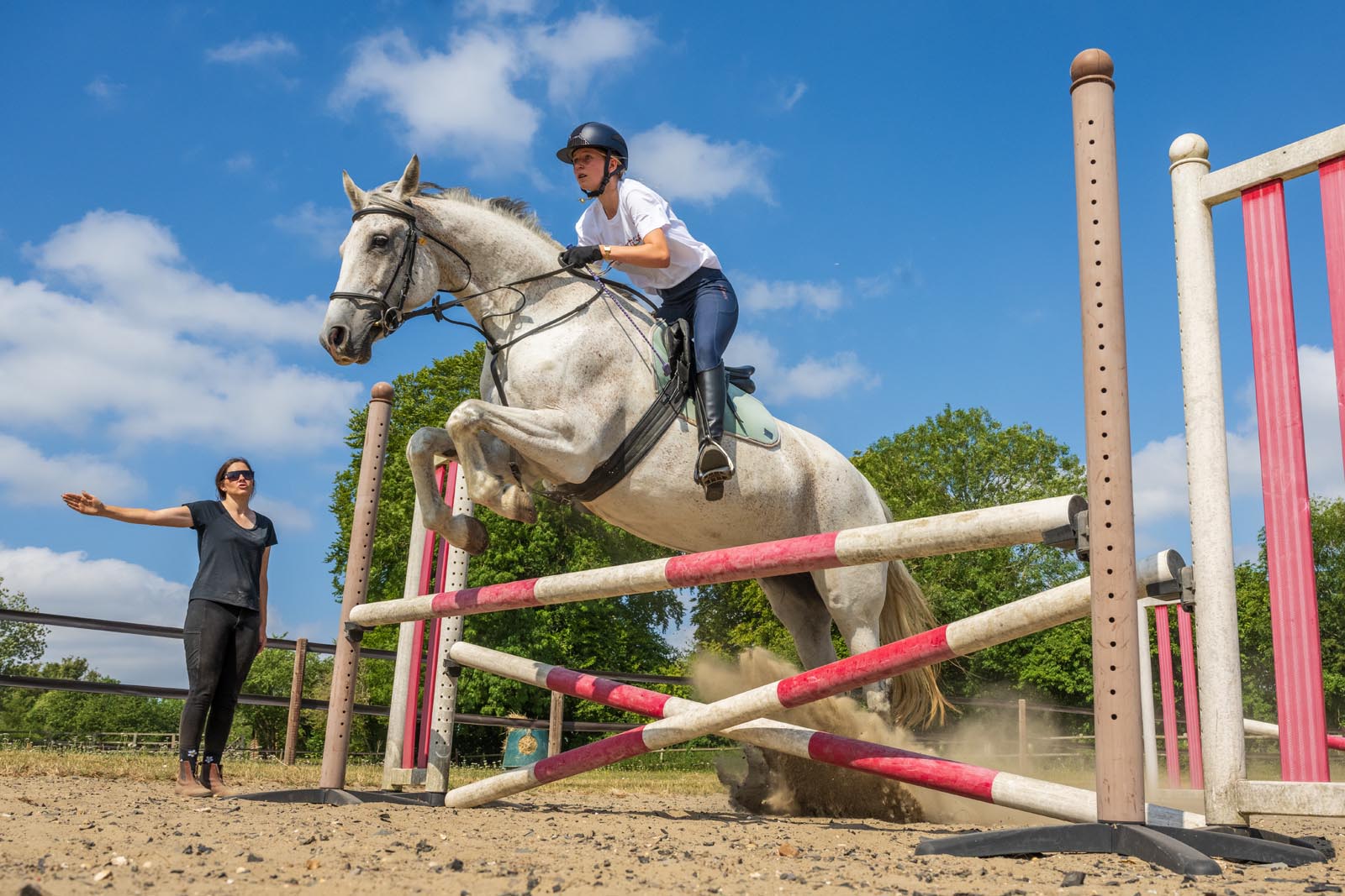 A young rider jumping with her white horse at an Exsportise Summer School.