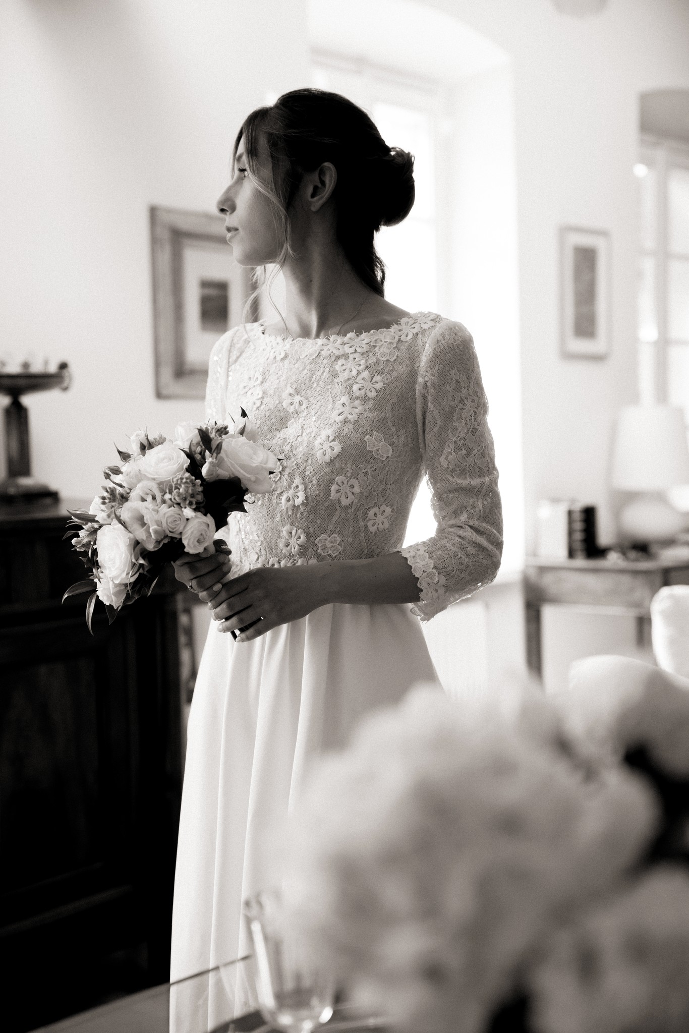 Sposa in abito di pizzo bianco con bouquet, ritratto di profilo nei preparativi matrimoniali a Villa Peroni Riva