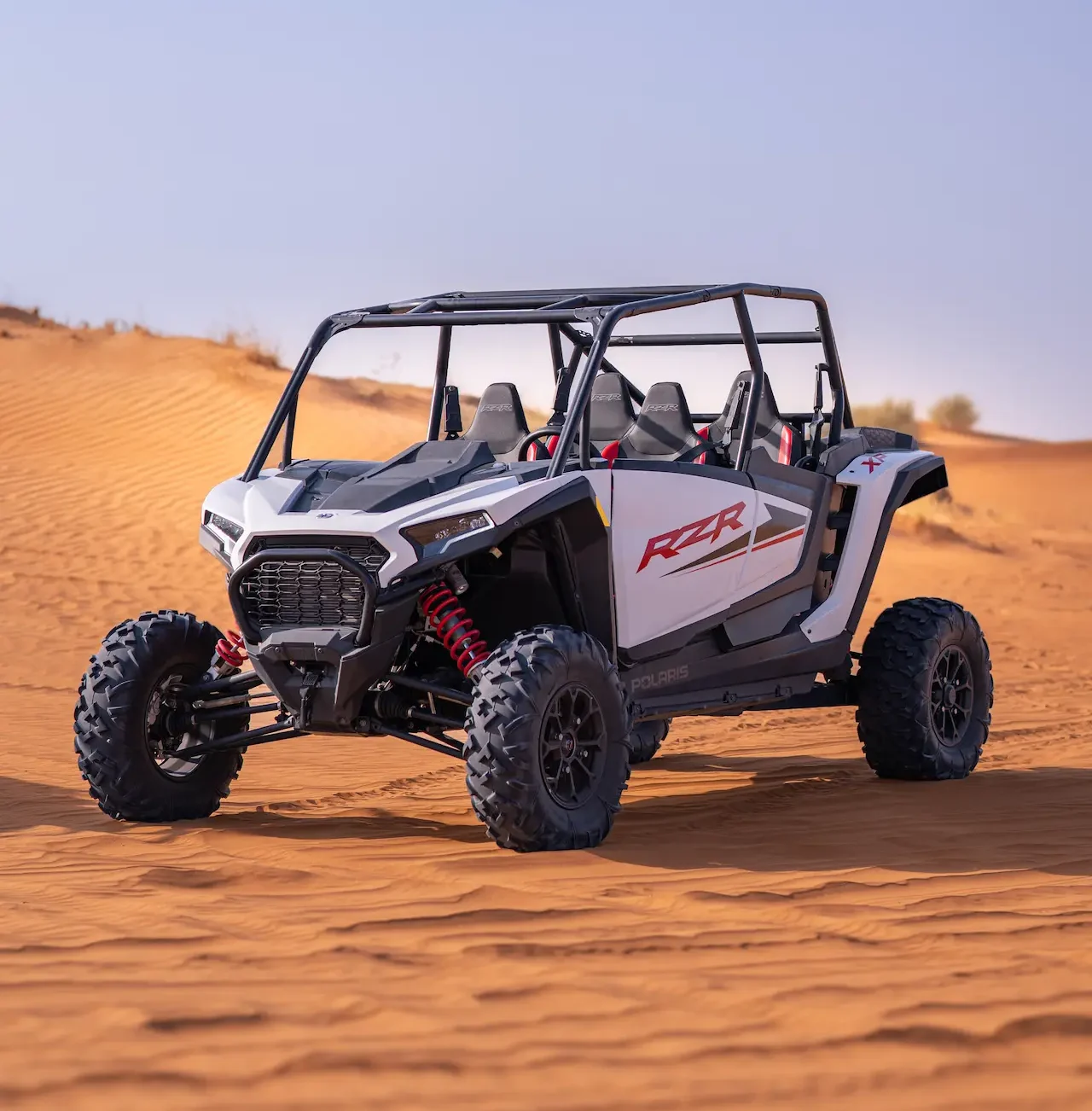A white Polaris RZR 1000XP 4-seater dune buggy parked on the orange sand dunes for a group buggy rental in Dubai with Dune Quest Tours