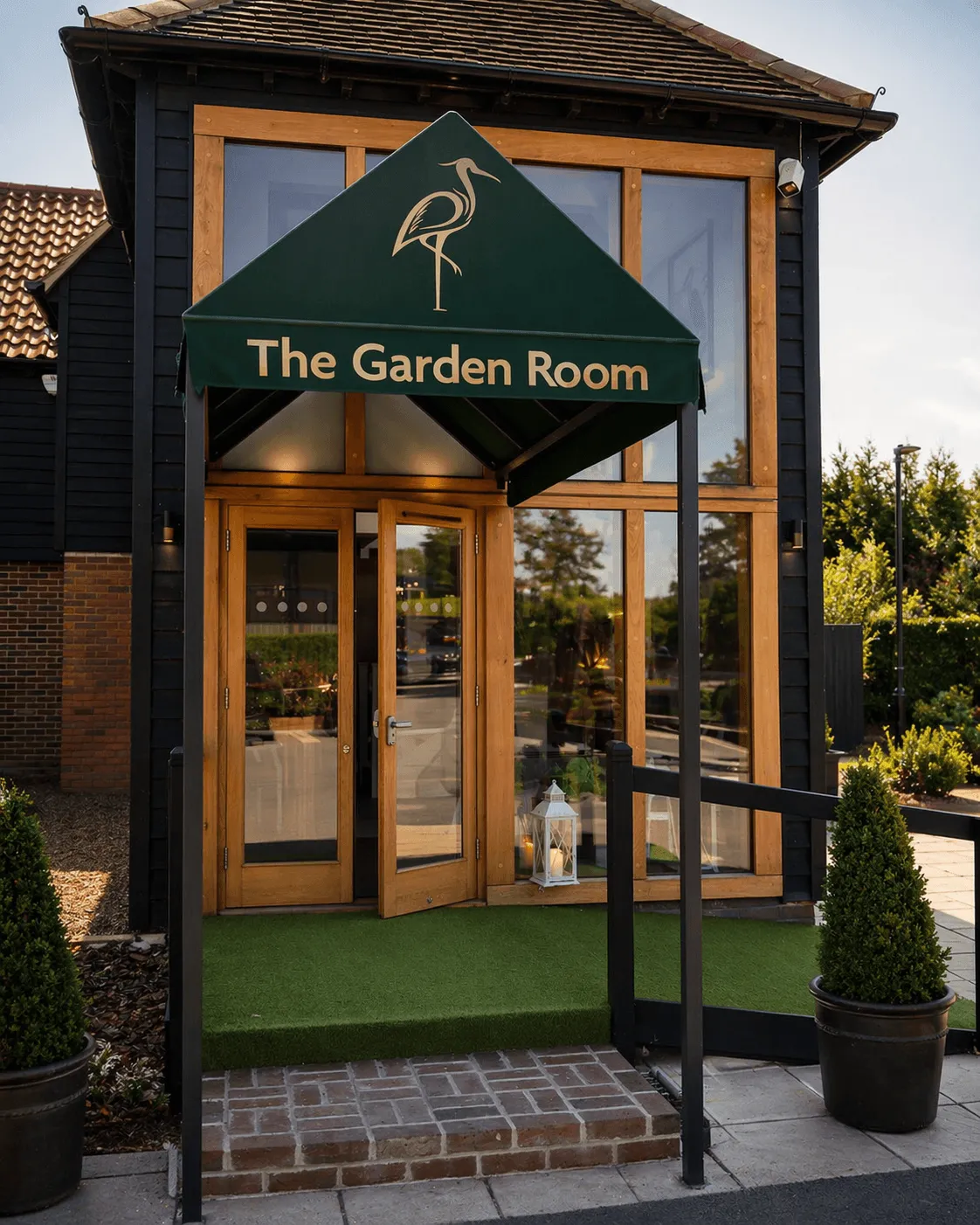 The Garden Room: entrance to a building with dark siding,  windows