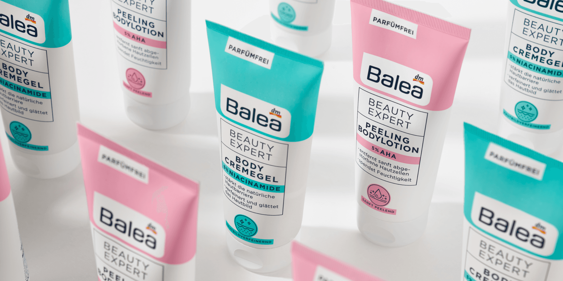 Markenwelt Balea Beauty Expert – parfümfreie Bodycare-Tuben in Türkis (Body Cremegel, 5% Niacinamide) und Rosé (Peeling Bodylotion, 5% AHA), dicht im Raster arrangiert vor weißem Hintergrund.
