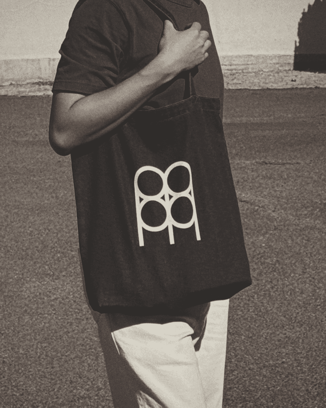 Meridian 88 monogram printed in cream on a black canvas tote, carried in sunlight