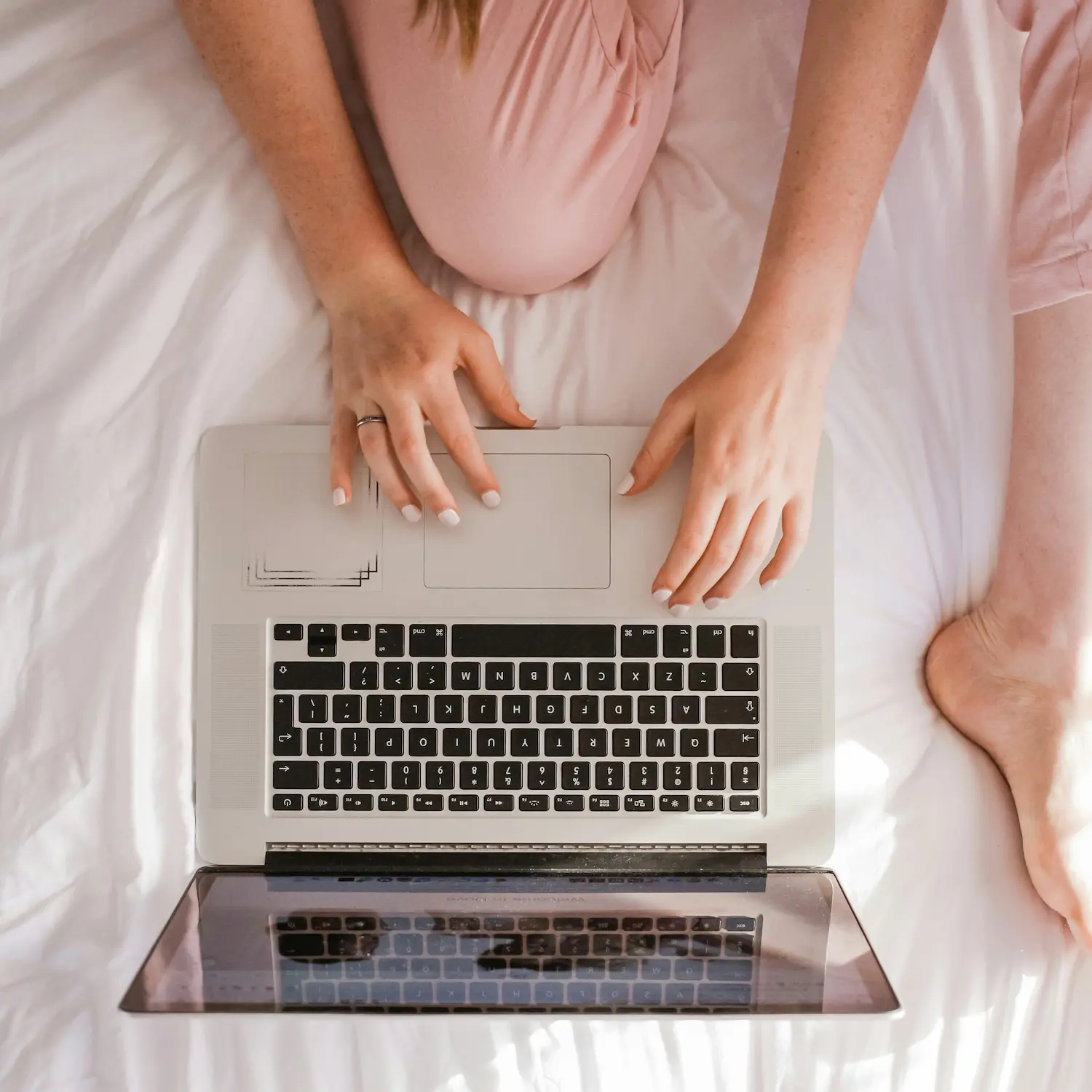 Woman sitting cross-legged on bed using laptop for online therapy session with a therapist in New York City