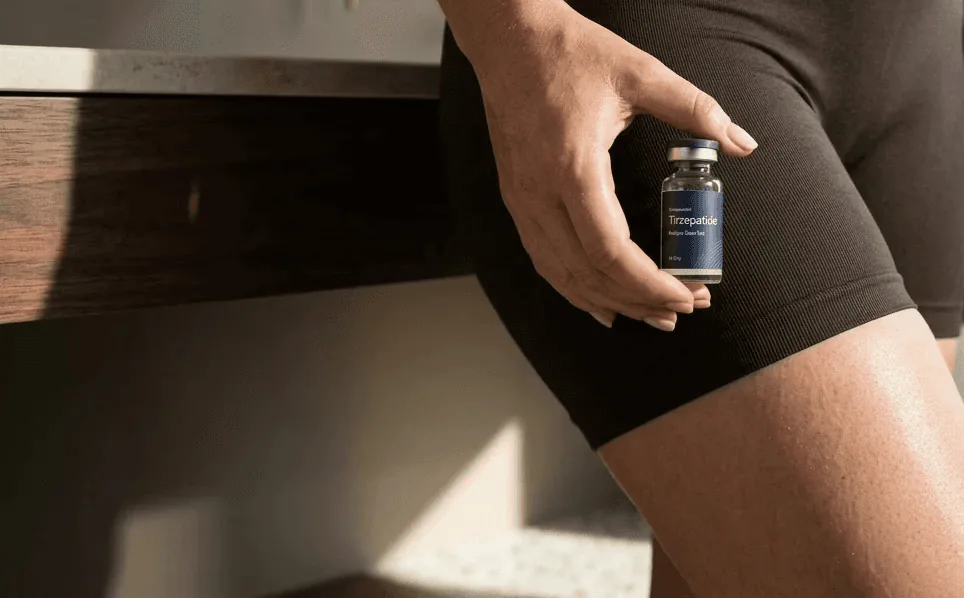 Close-up of a hand holding a small vial against dark shorts