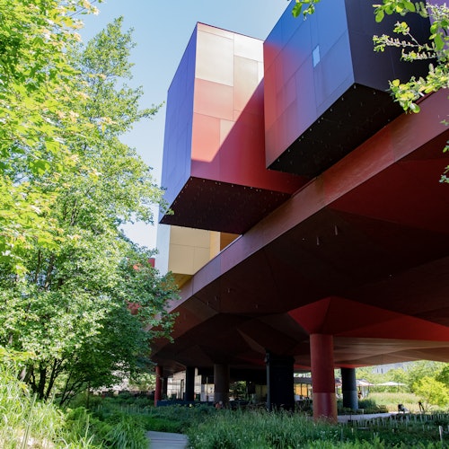 现代建筑,拥有生动的红色、黄色和橙色立方体结构,周围环绕着郁郁葱葱的绿色树木和植被。