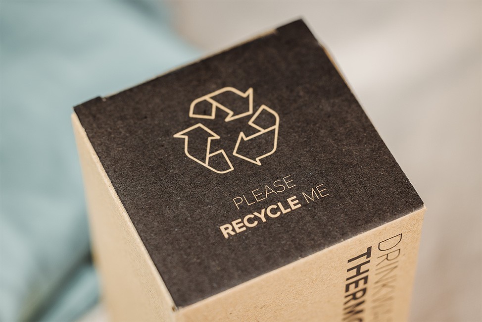 Close-up of a cardboard box with a recycling symbol and "Please recycle me" printed on the top