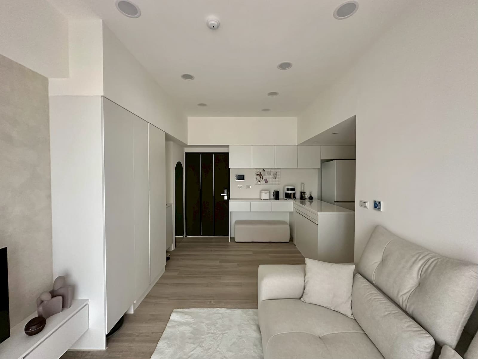 屋研所輕裝修｜極簡白色系開放式客廳，淺木地板搭配灰色布沙發與隱藏式廚房收納