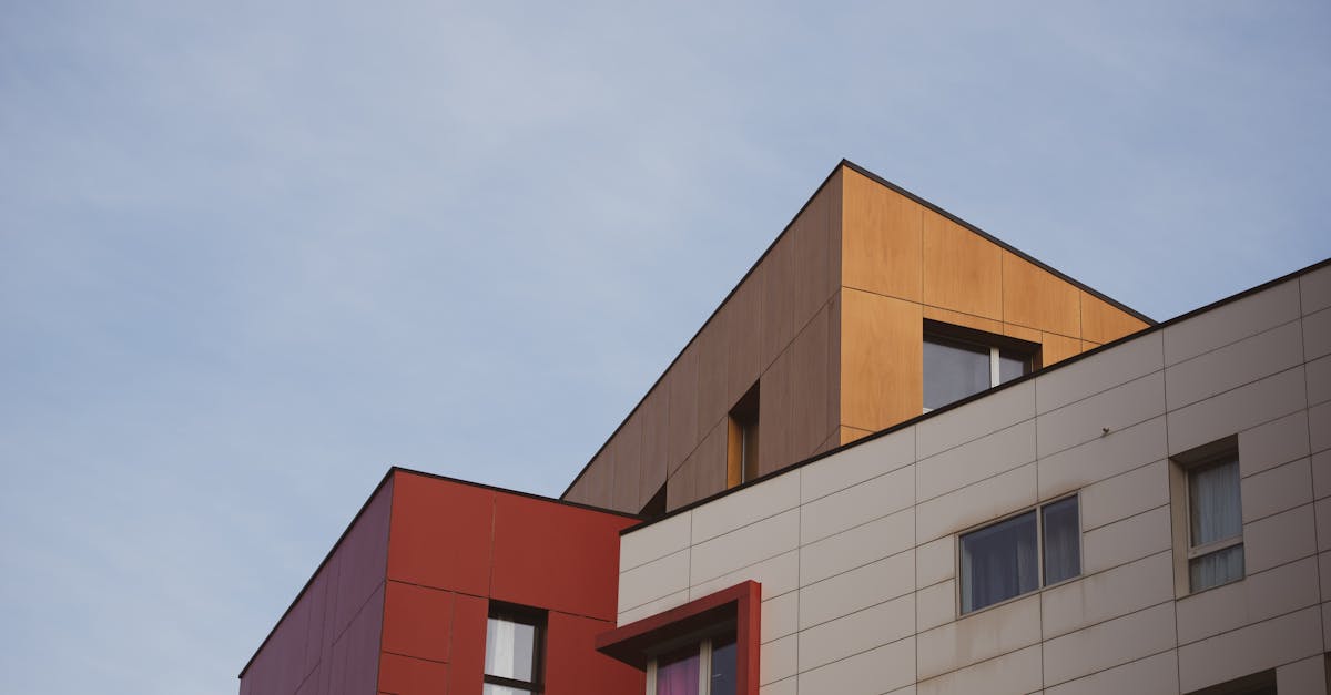 Contemporary building with geometric shapes and red, brown, and white panels under a clear sky.