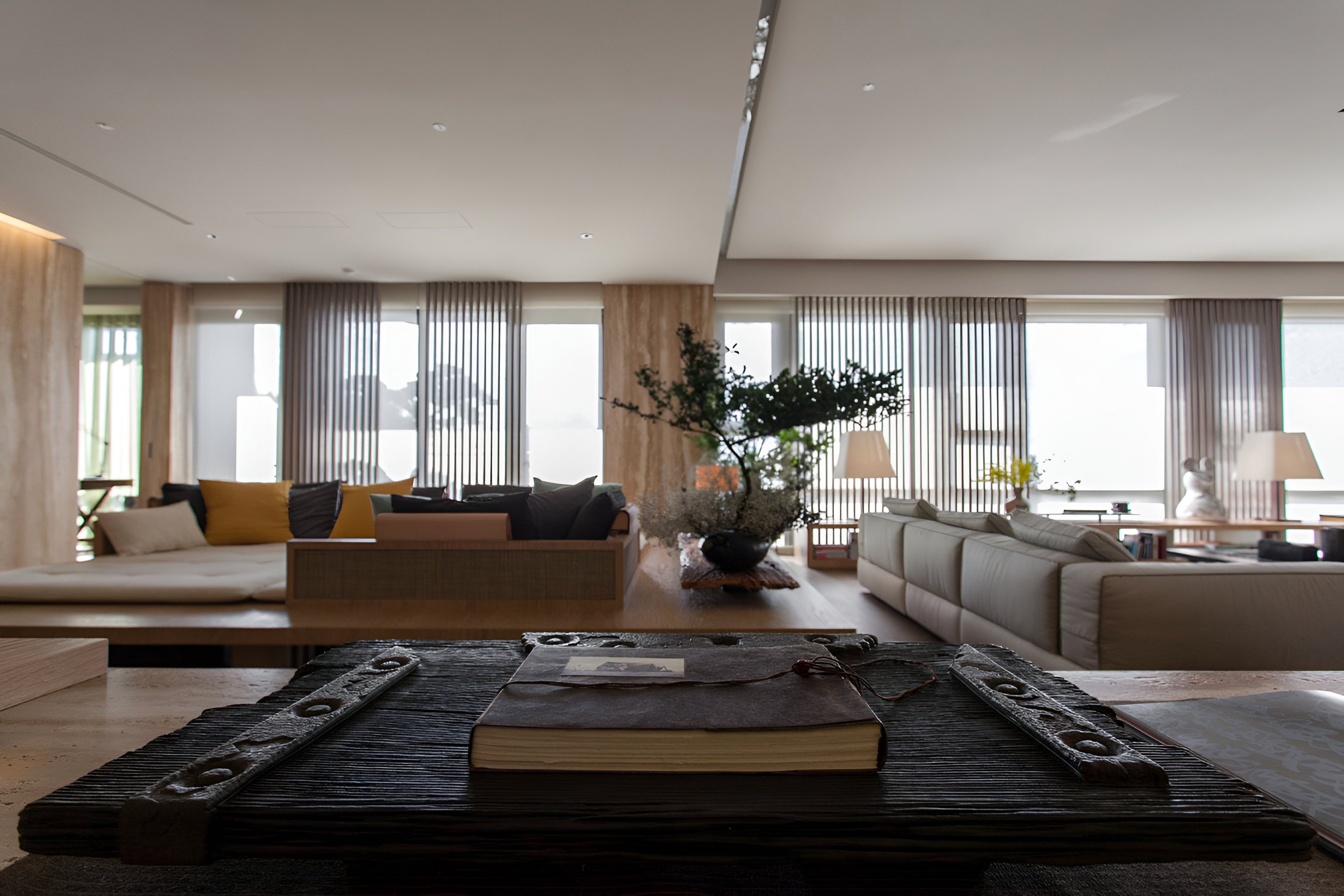 客廳焦點為近景的皮革裝訂筆記本與鐵件裝飾，背景為明亮開放式會客空間