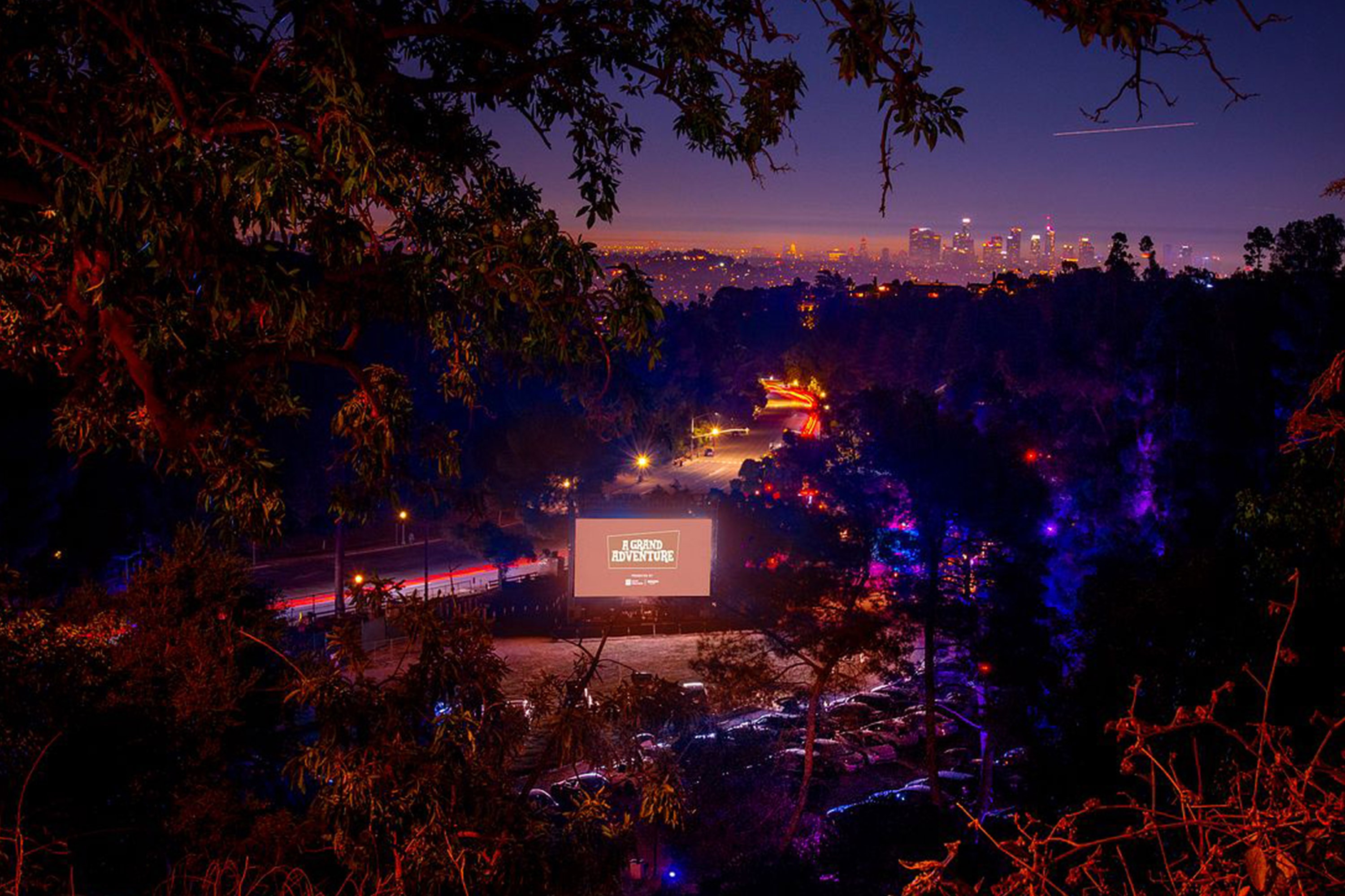 Night time aerial view of cars parked in a drive-in movie theater.