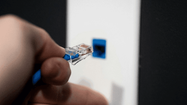 인터넷 연결을 위해 파란색 이더넷 케이블 커넥터를 하얀색 벽면 포트에 삽입하기 진적의 클로즈업 모습입니다.