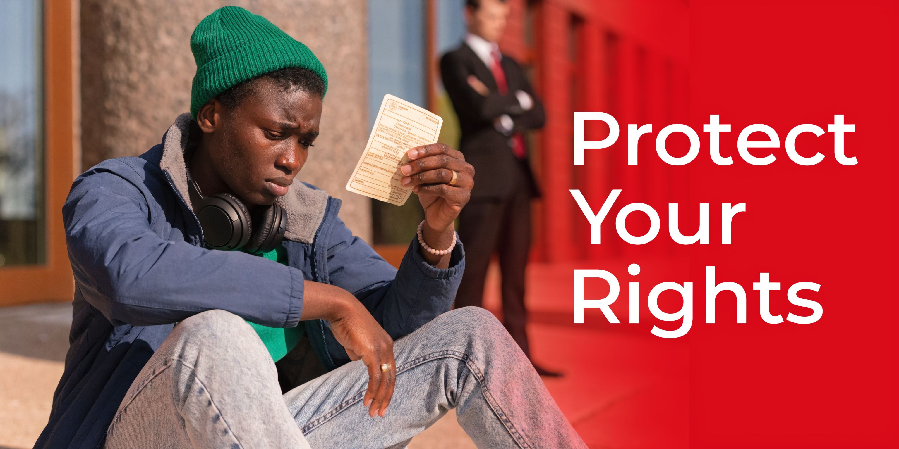 A young man sits on steps looking at a traffic ticket while a lawyer stands behind him.