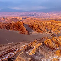 Paisagem desértica do Vale da Lua em San Pedro de Atacama, com formações rochosas e dunas ao entardecer