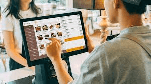 Restaurantpersonal nimmt eine Bestellung an einem Tablet-Kassensystem auf – das Händlergeschäft, auf das sich Global Payments nun konzentriert.