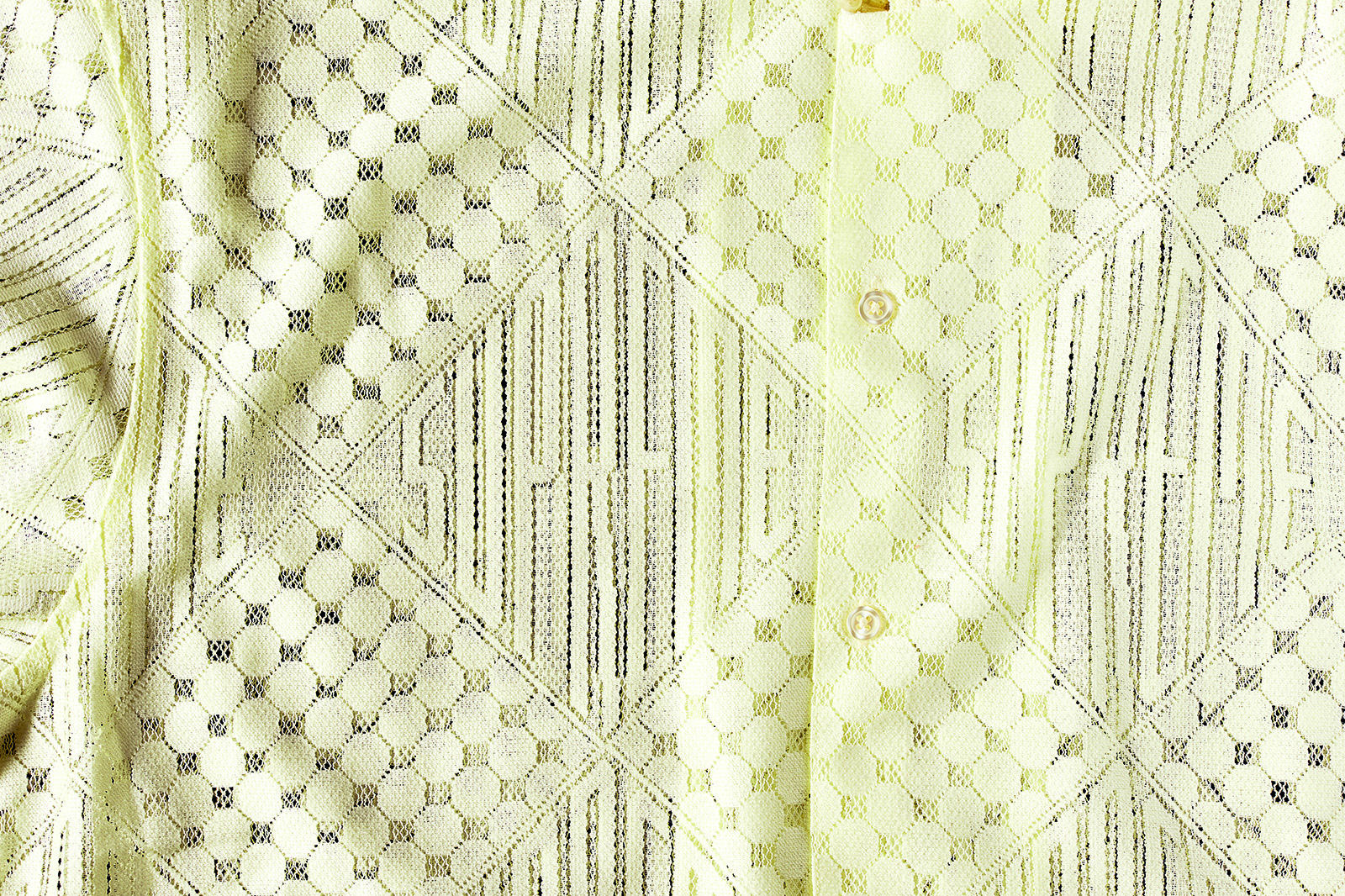 Close-up of a textured, light yellow fabric with a mesh-like pattern and subtle, wavy design details.