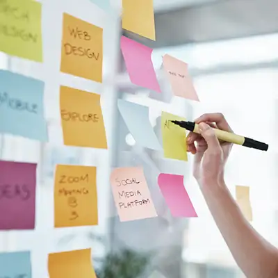 UI/UX designer sketching app wireframes on paper with pen. Mobile app design process.