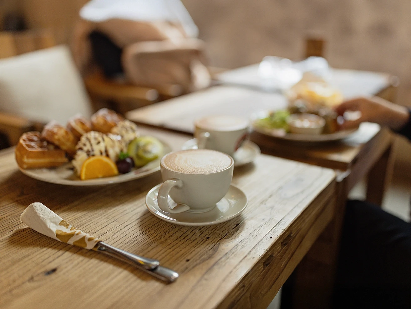 A red gondola car travels on cables over a green valley with a large lake and a town on its shore.