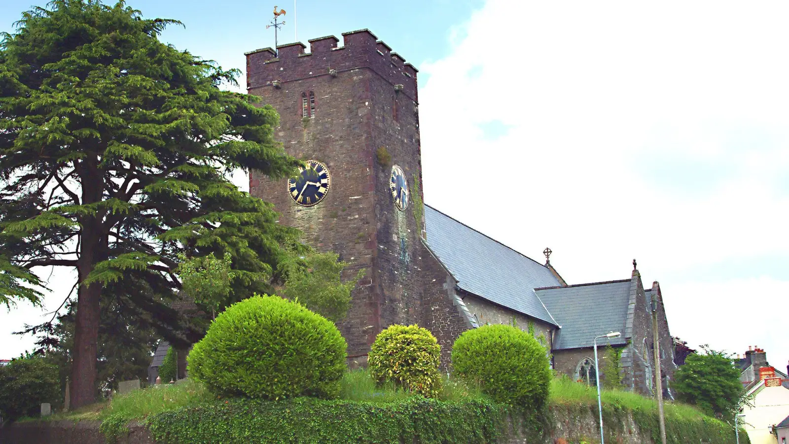 The historic stone church tower in Llandeilo framed by a large tree