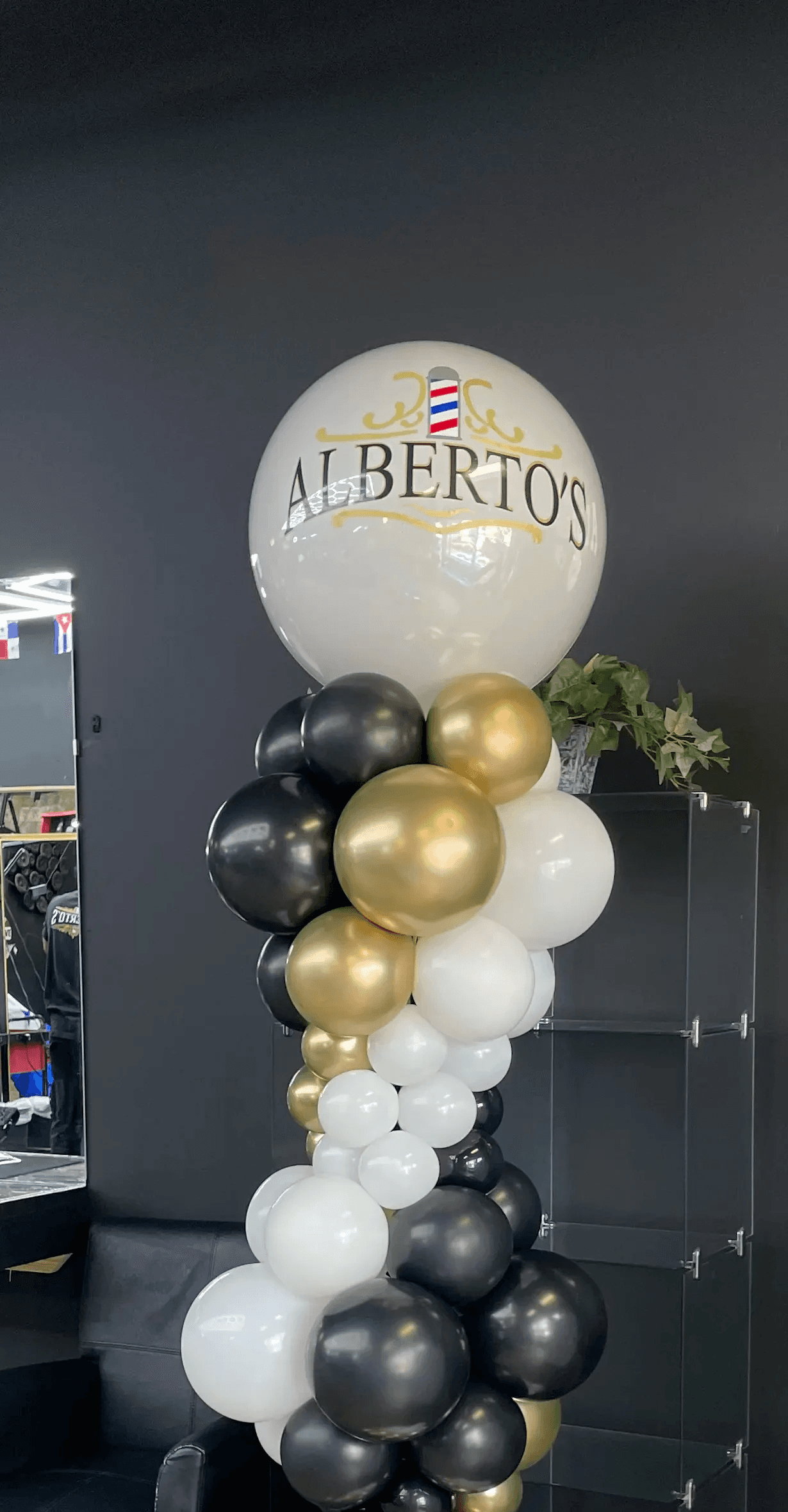 Elegant balloon column in a sophisticated black, white, and gold color scheme, arranged in an organic style with a mix of sizes for a classy and modern look. Ideal for upscale events or formal celebrations. Susa’s Sweets & Balloons.