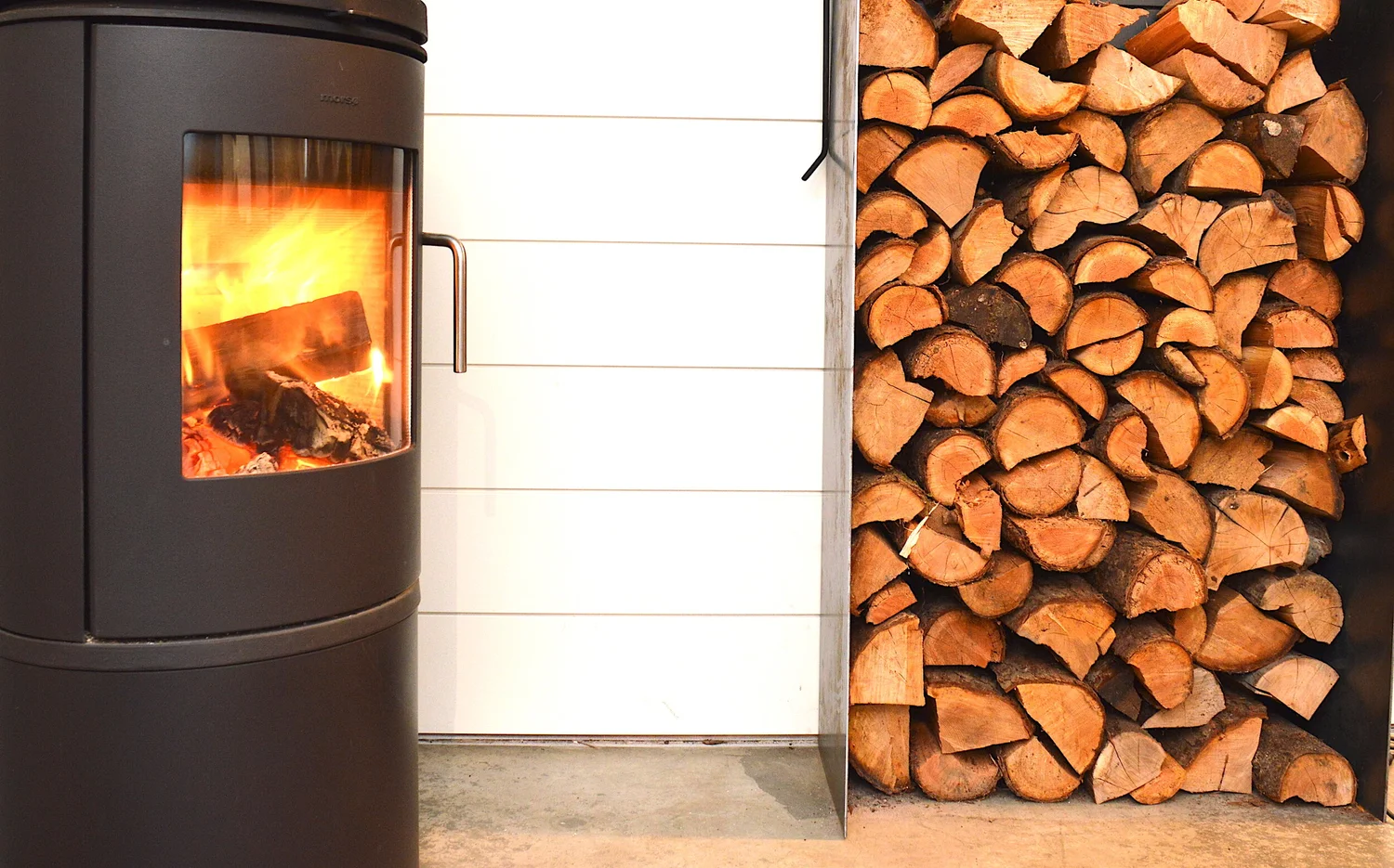 Modern two-story home with large glass windows, warmly lit interiors, and a balcony. Surrounded by trees and a manicured lawn at dusk. Cozy ambiance.