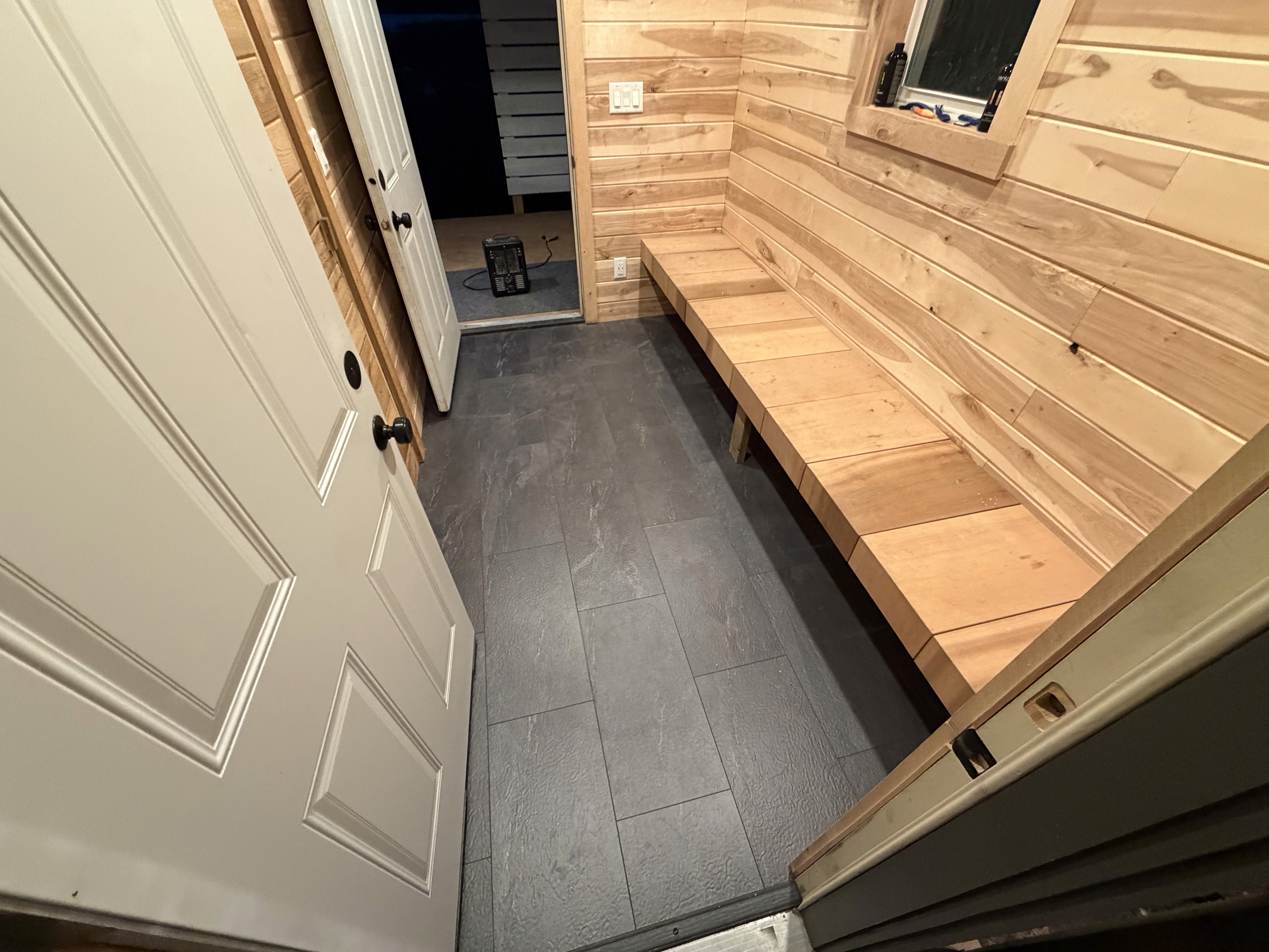 Modern bathroom featuring a walk-in shower, wooden vanity, round mirror, and elegant marble tiles.