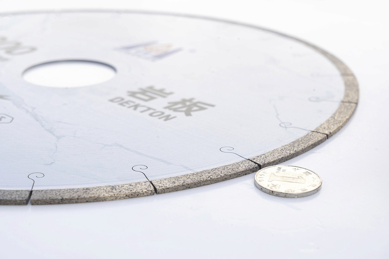 Close-up of the edge of a Diamond Saw Blade For Dekton, with a coin placed next to it for size reference.