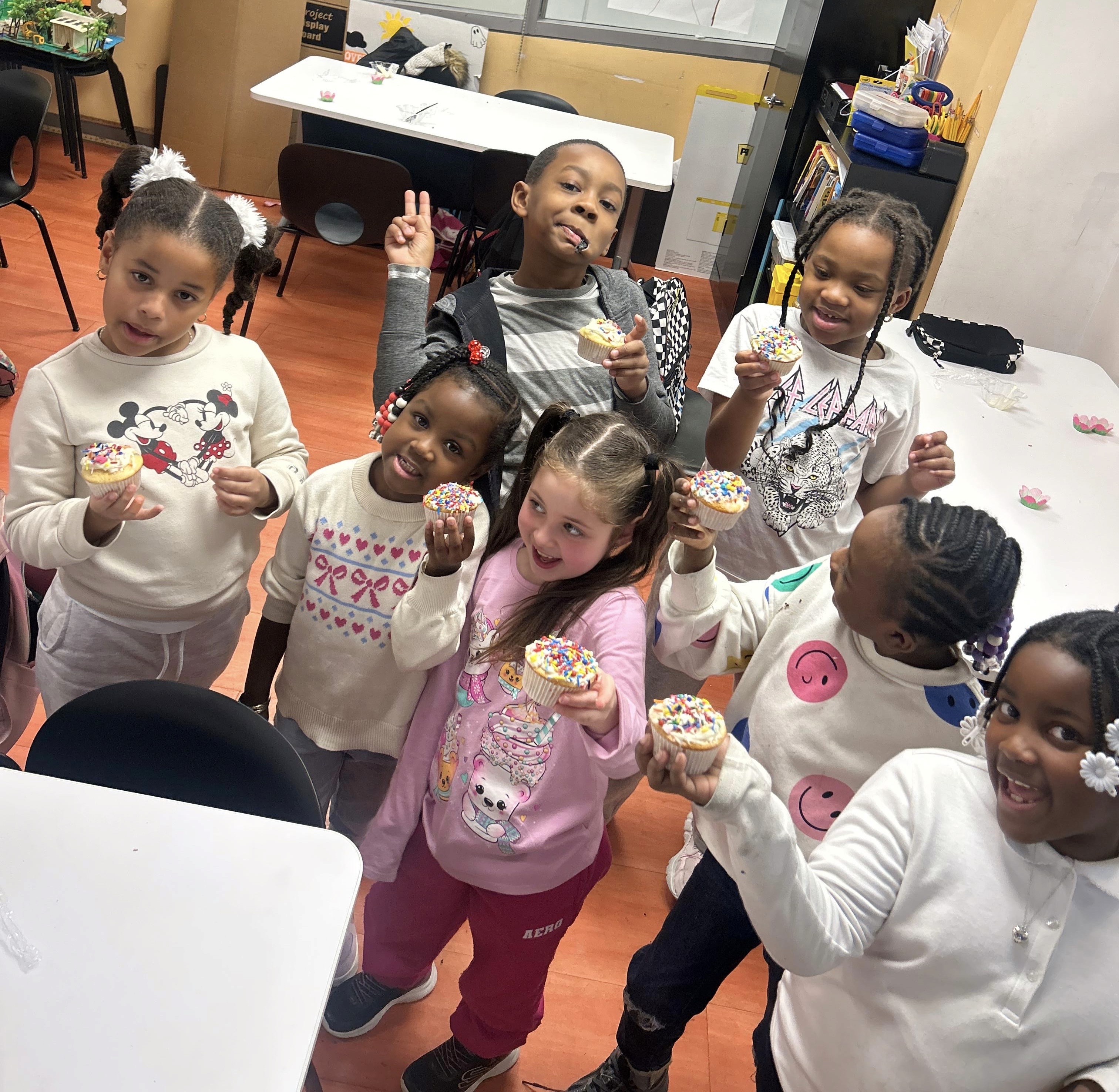 Afterschool students proudly show off their decorated cupcakes.