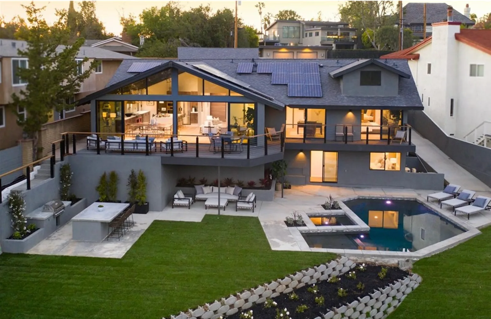 A connected backyard Terraces and broad paved areas connect a hillside home with an outdoor kitchen, lounge seating, lawn and pool.
