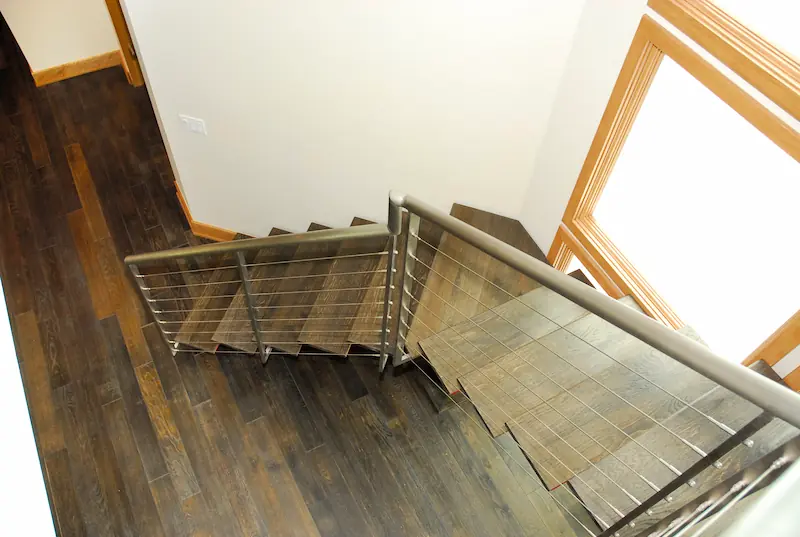Above view of modern staircase with dark wooden treads and stainless steel handrail. Irvine Transitional Modern Project. Photo by Chris Darnall.