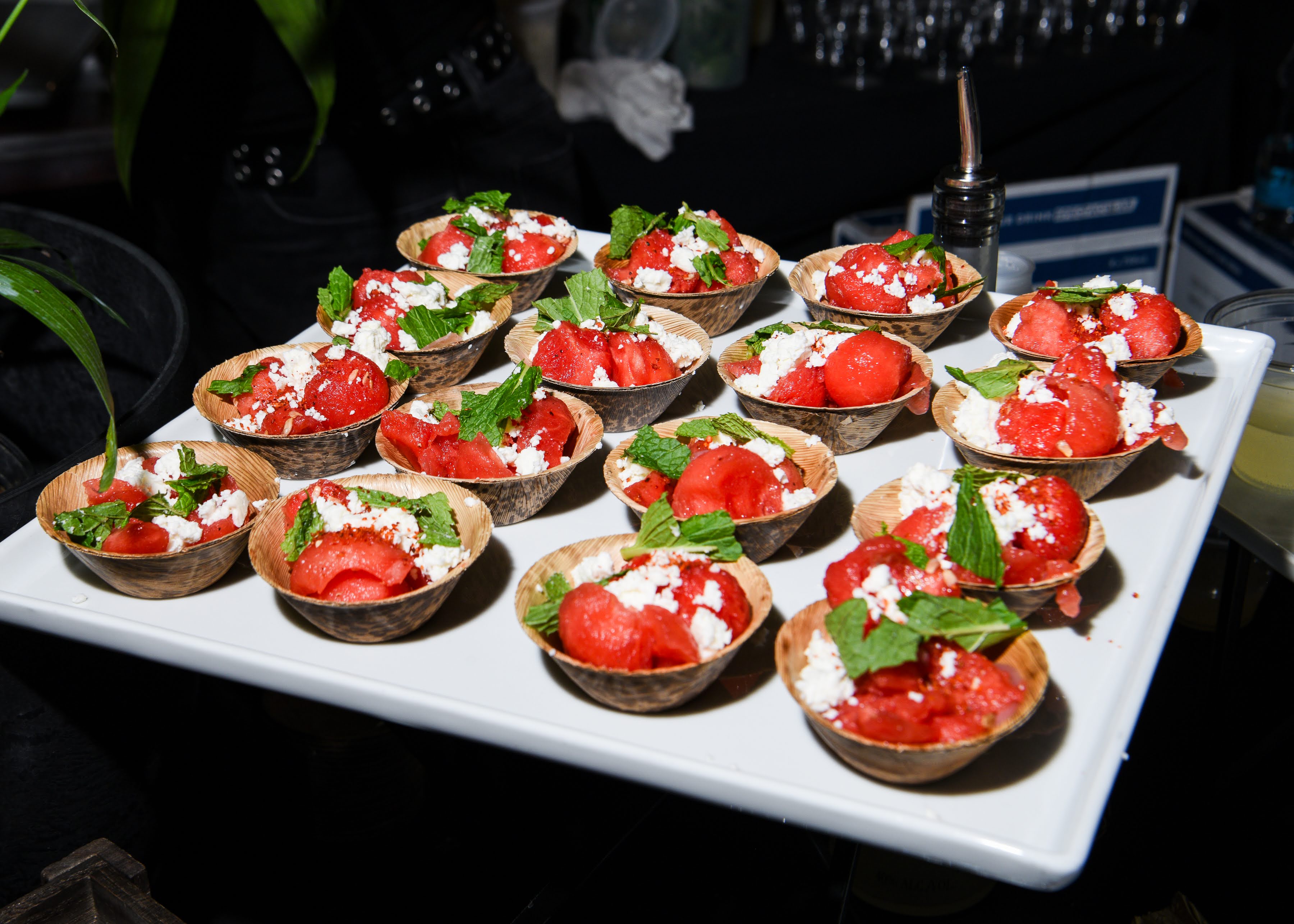 A decorative dish with red fruit, white garnish, and mint leaves.