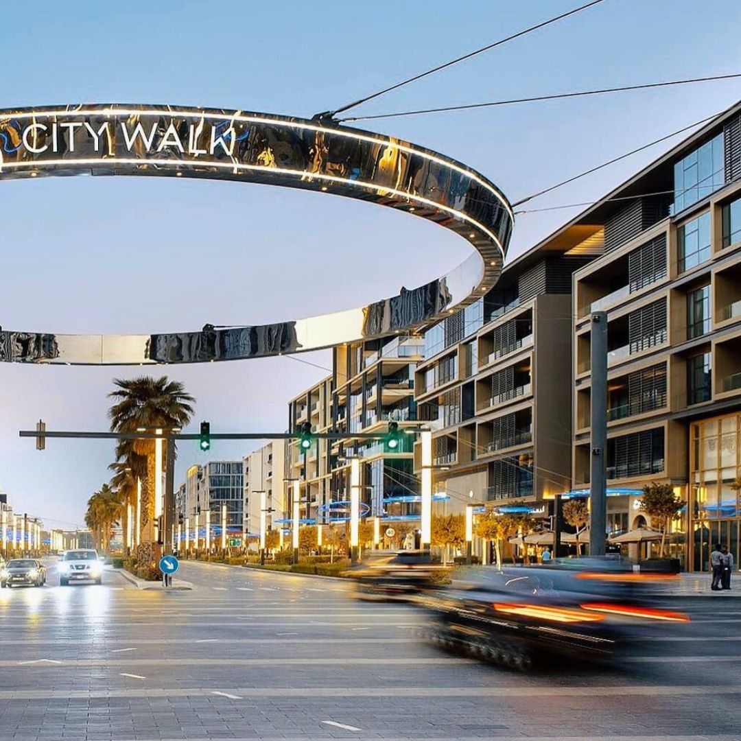 City Walk in Dubai with modern buildings, palm trees, and cars passing by.