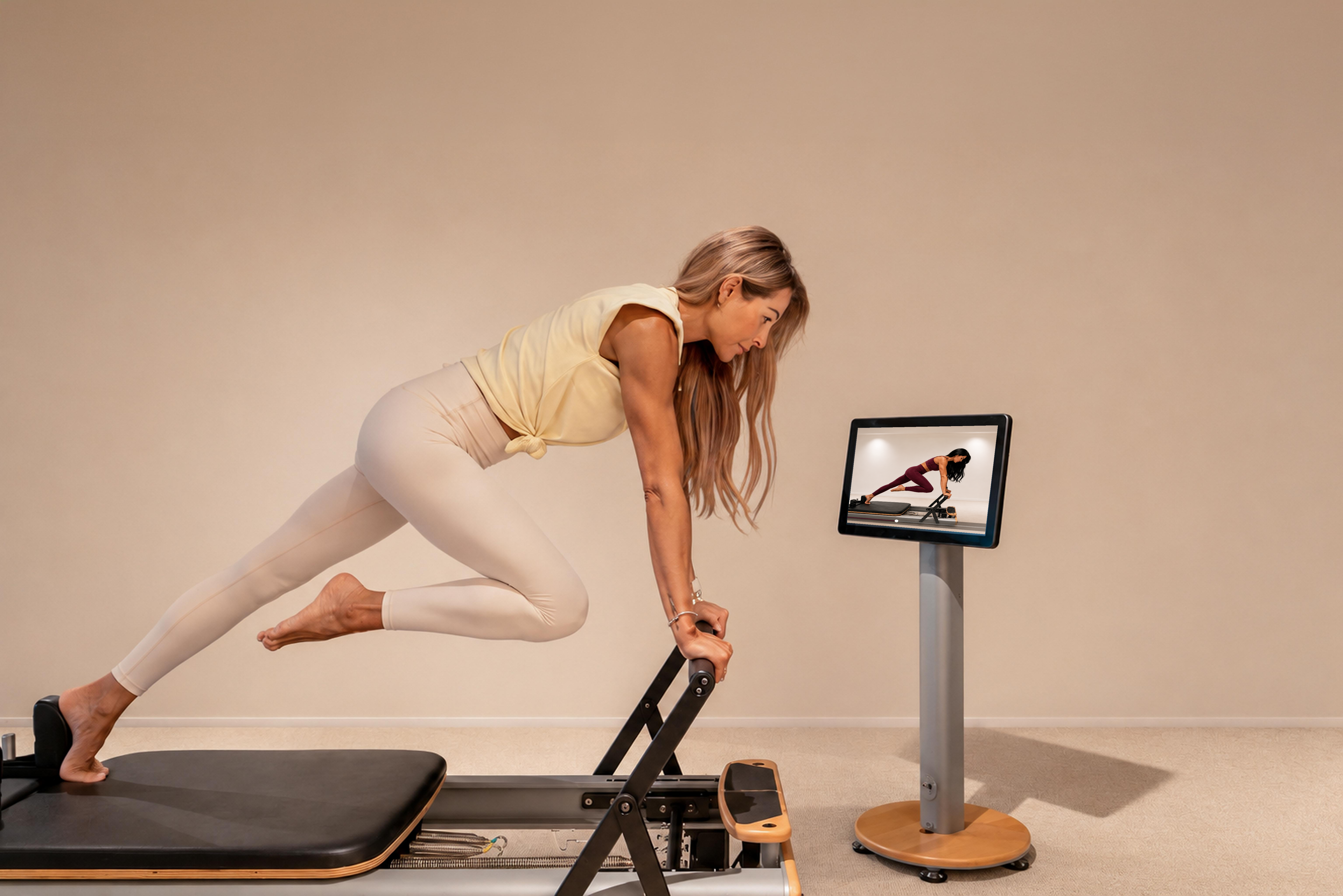 Woman following a guided Digital Reformer workout on the in-studio screen