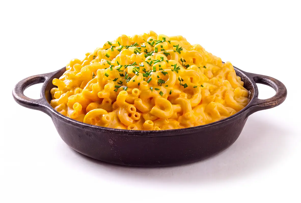 Creamy macaroni and cheese garnished with chopped herbs in a cast-iron serving dish.