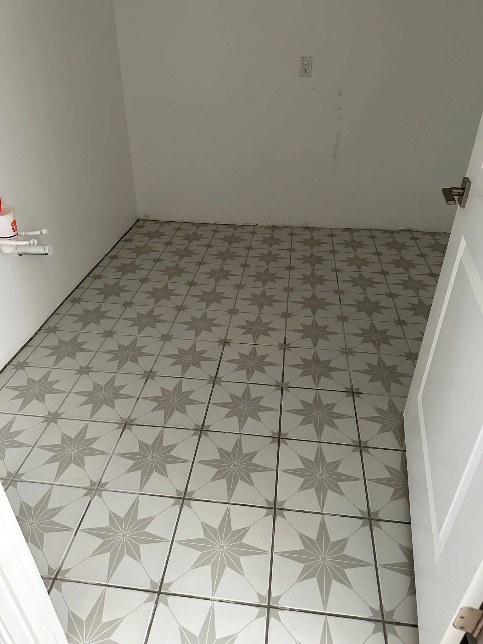 Modern small room with patterned star-shaped tile flooring in a new home under construction.