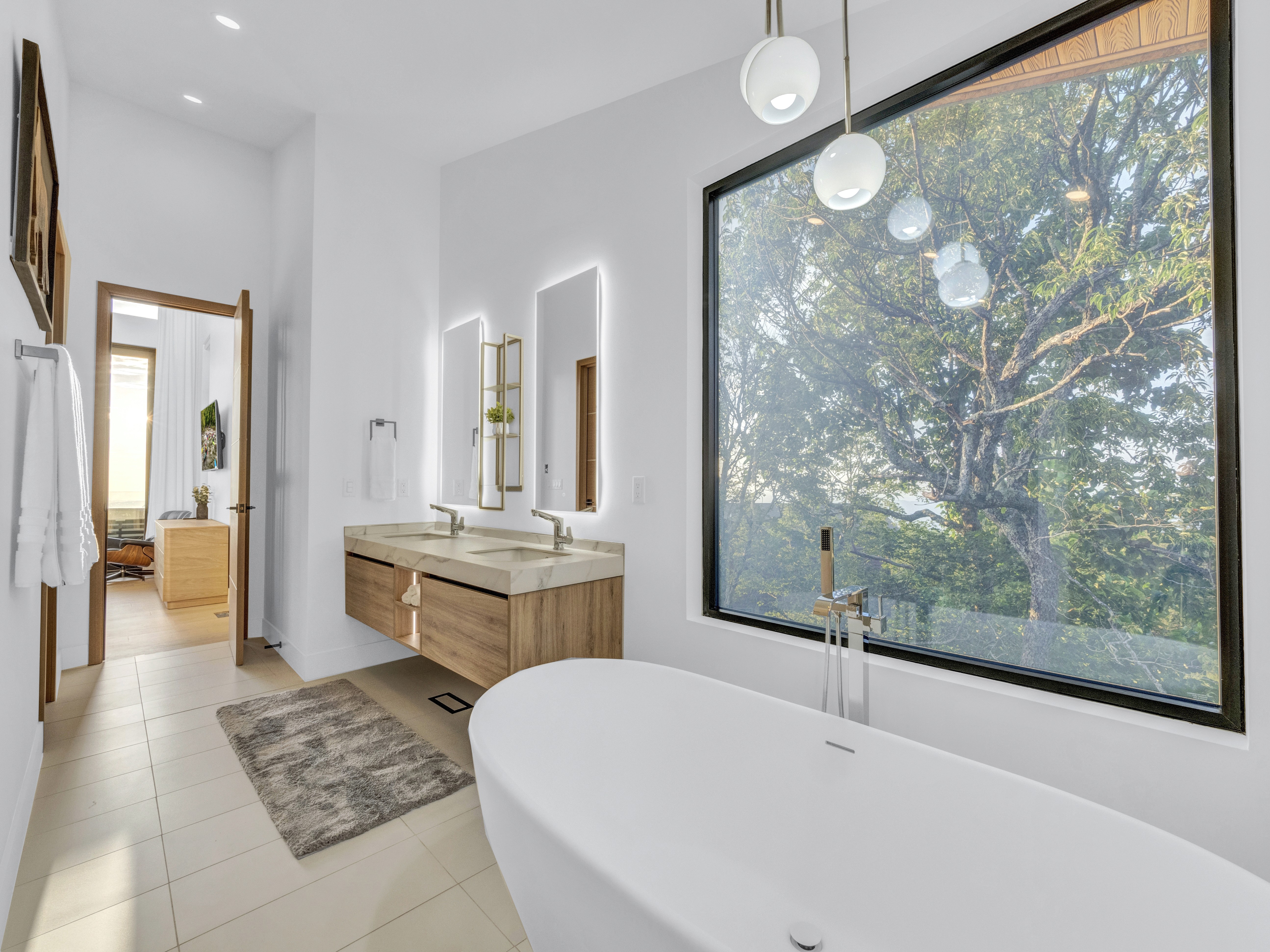 The master bathroom bathed in warm afternoon light, highlighting the connection between the indoor luxury and the outdoor forest