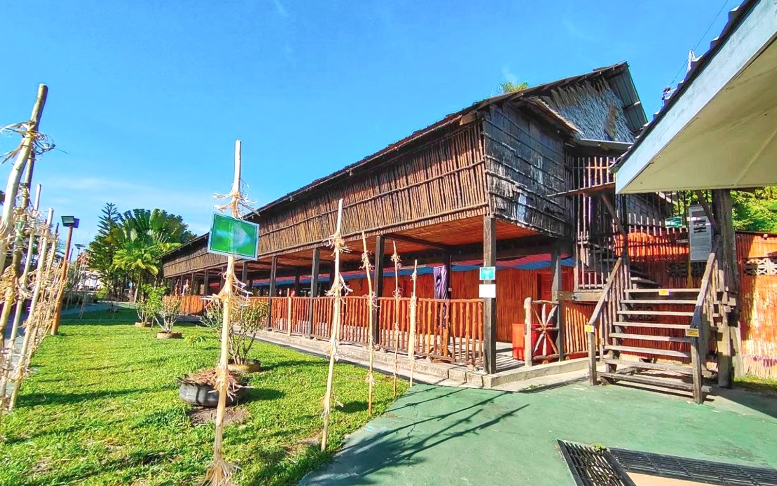 Traditional wooden building at Koisaan Cultural Village, Sabah, surrounded by greenery.