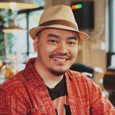 Ario Anindito smiling with a light brown hat and a red polo