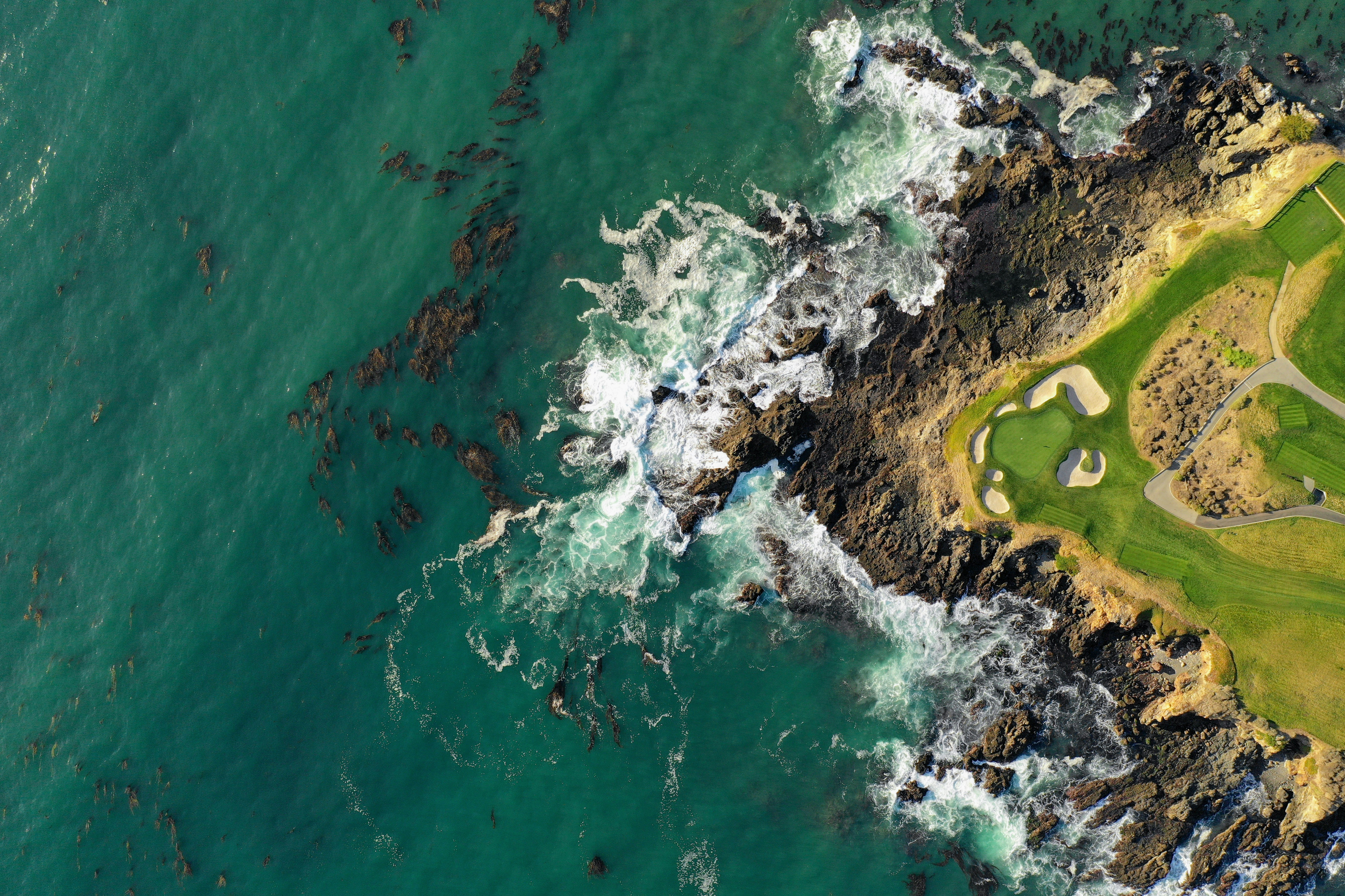 aerial view of golf course next to an ocean