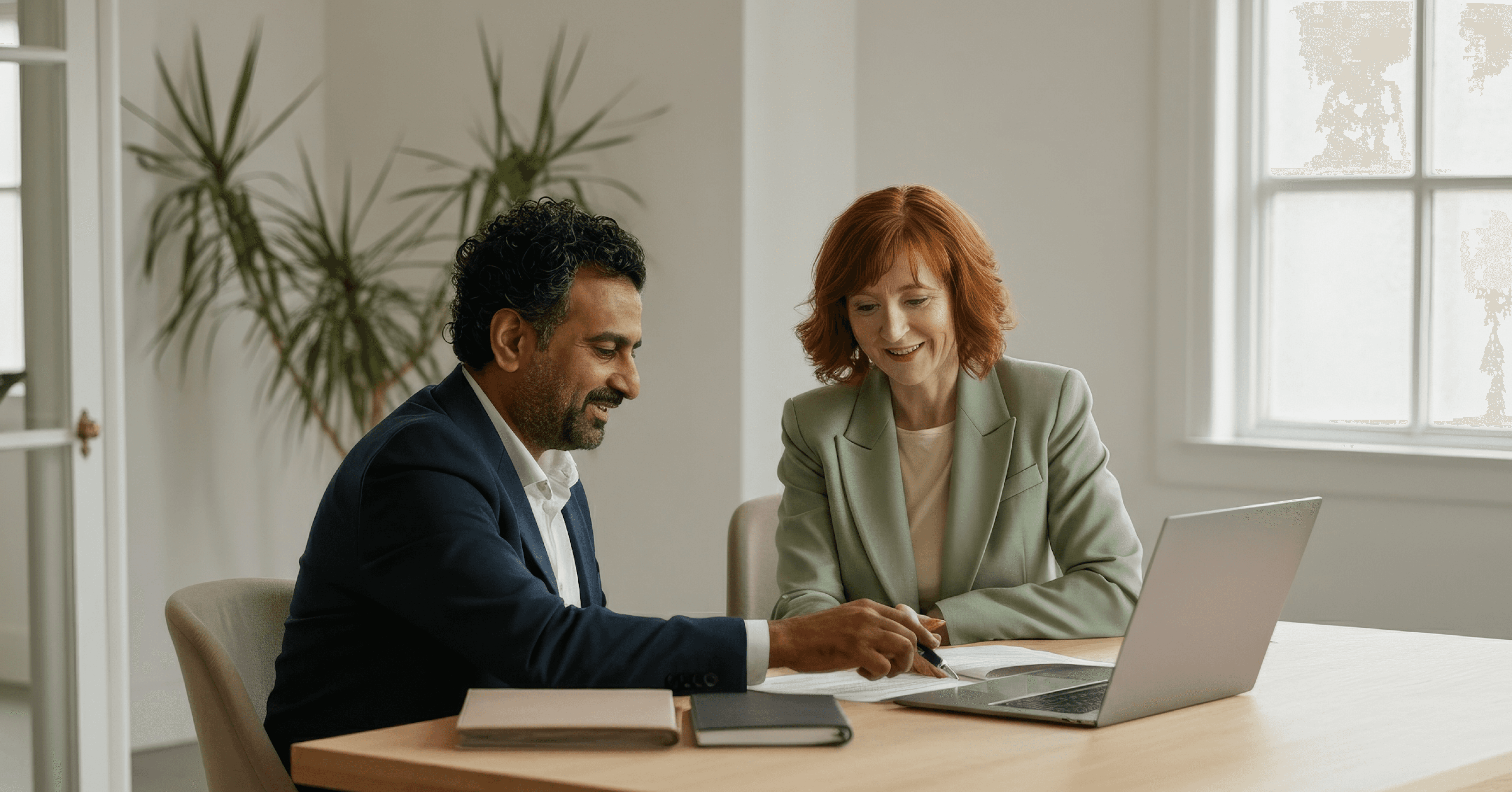 Two professional colleagues collaborating on a project with a laptop and papers